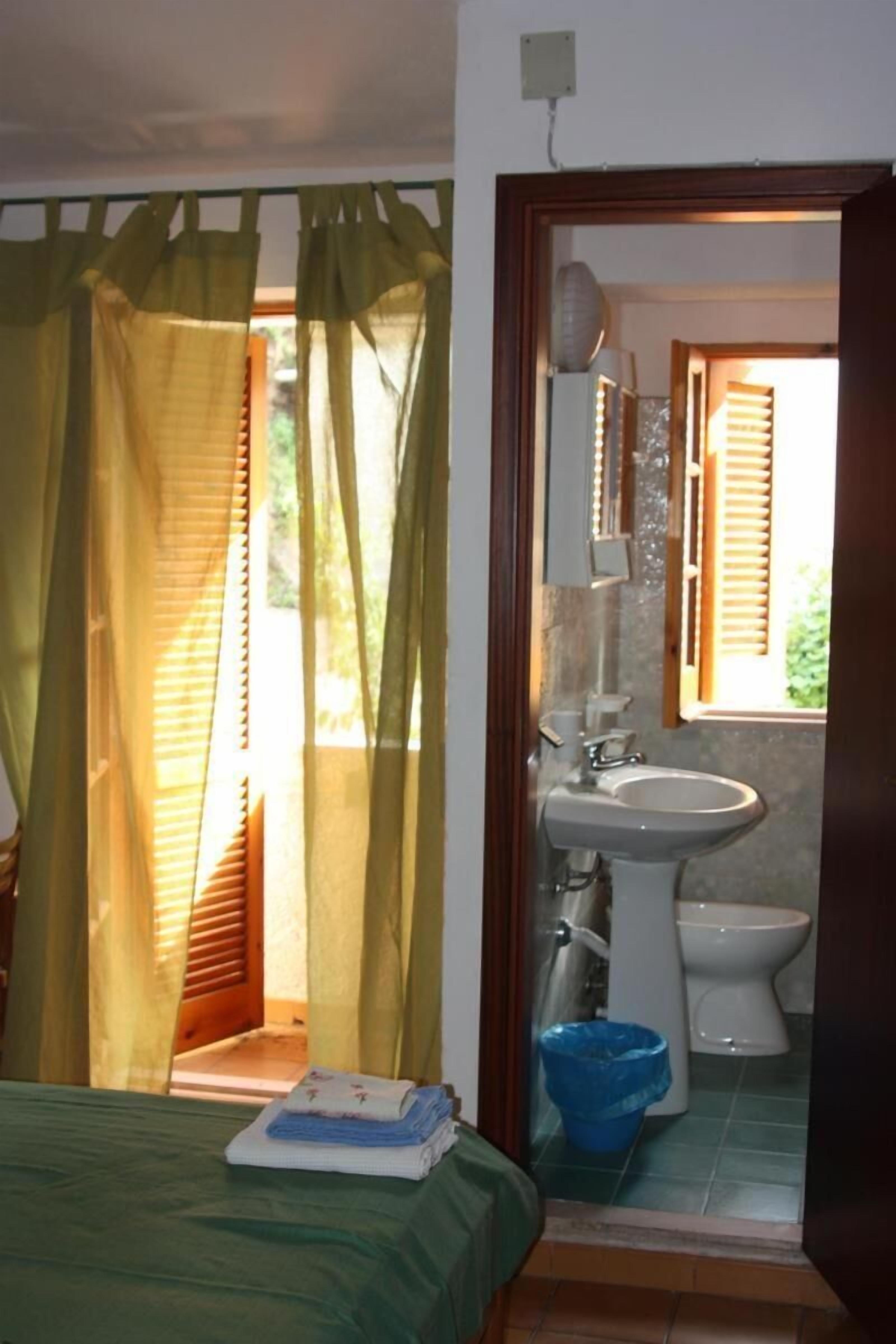 A bathroom with a sink, toilet, and a blue trash bin.