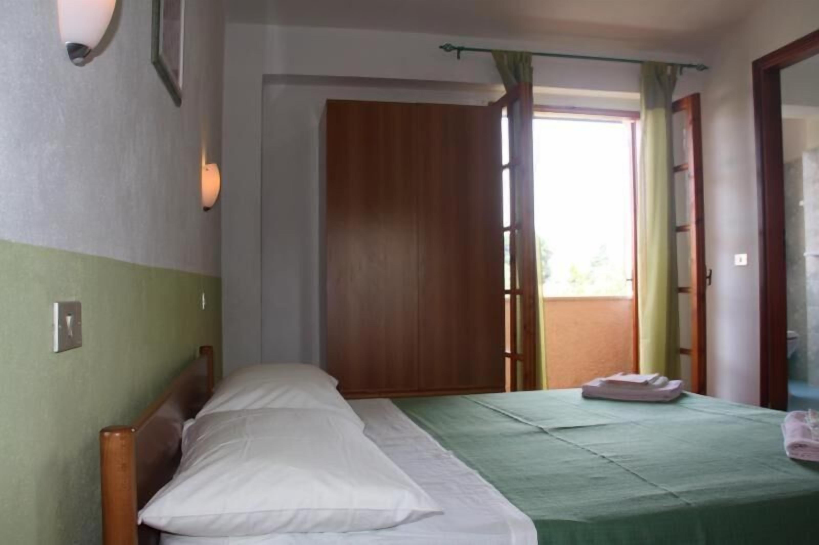Un dormitorio con una cama, una puerta de madera y una ventana con cortinas.