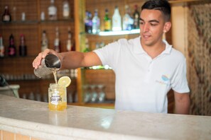 Una persona sirve una bebida en un tarro con una rodaja de limón encima.