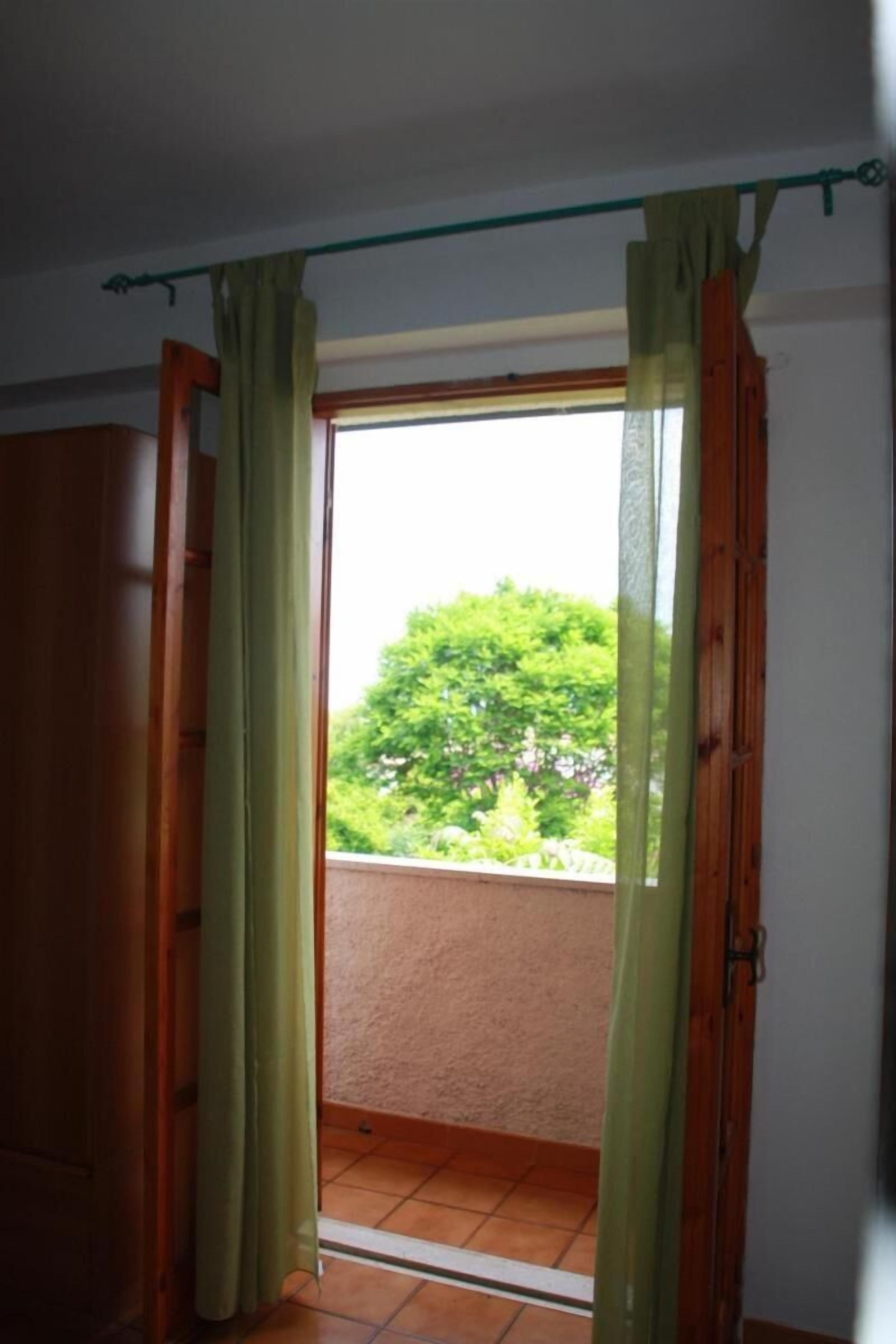 A room with a sliding glass door leading to a balcony.