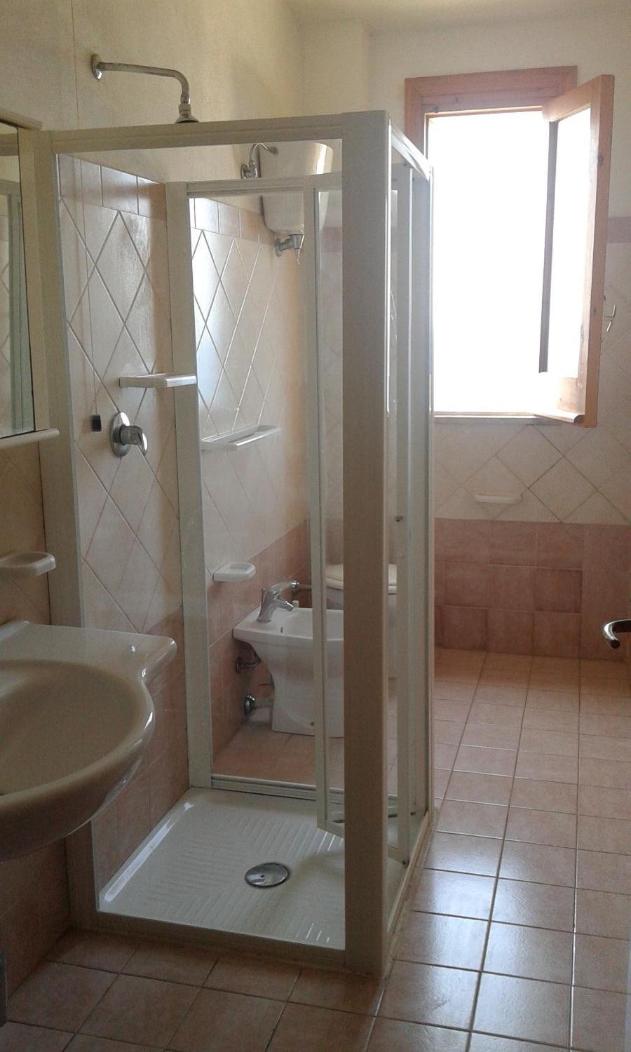 Et badeværelse med brusekabine med glasvægge, vask og toilet.