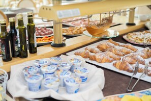 Un bufé con diversas opciones de comida, incluyendo bollería, carnes y productos lácteos.