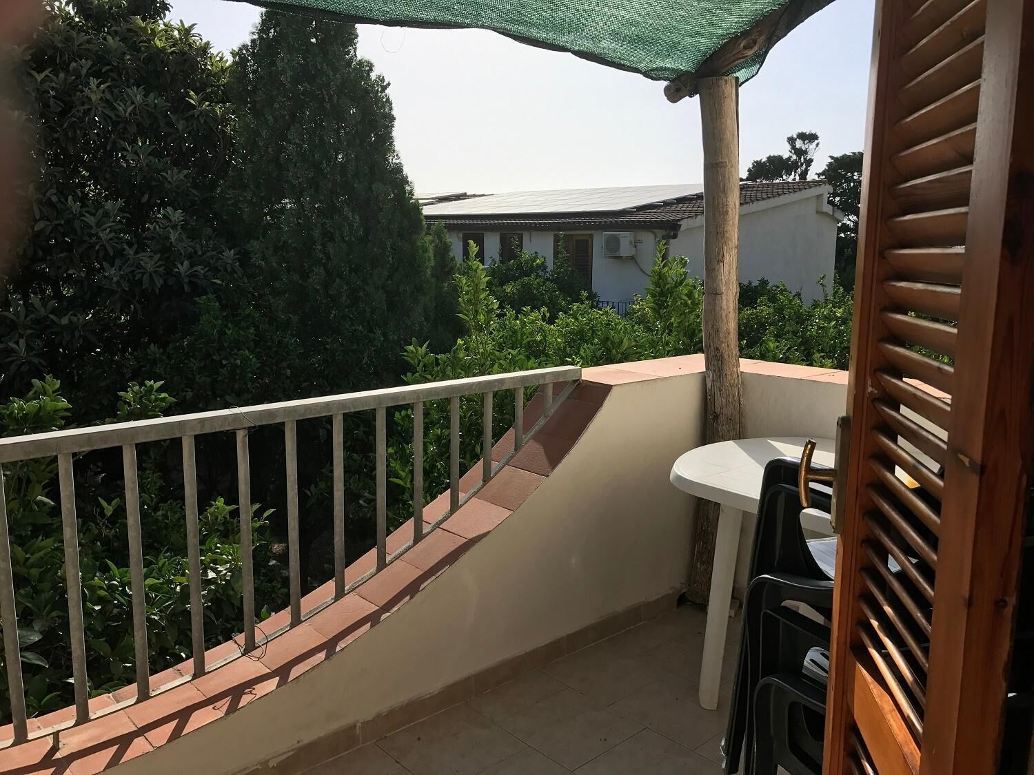 Un balcone con ringhiera bianca, un tavolino e una sedia.