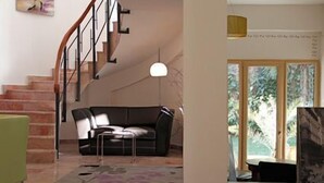 Una sala de estar con escalera, un sofá y una lámpara colgante.