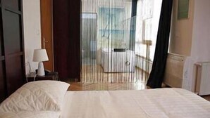 Habitación de hotel con una cama, una mesita de noche y vistas al exterior.