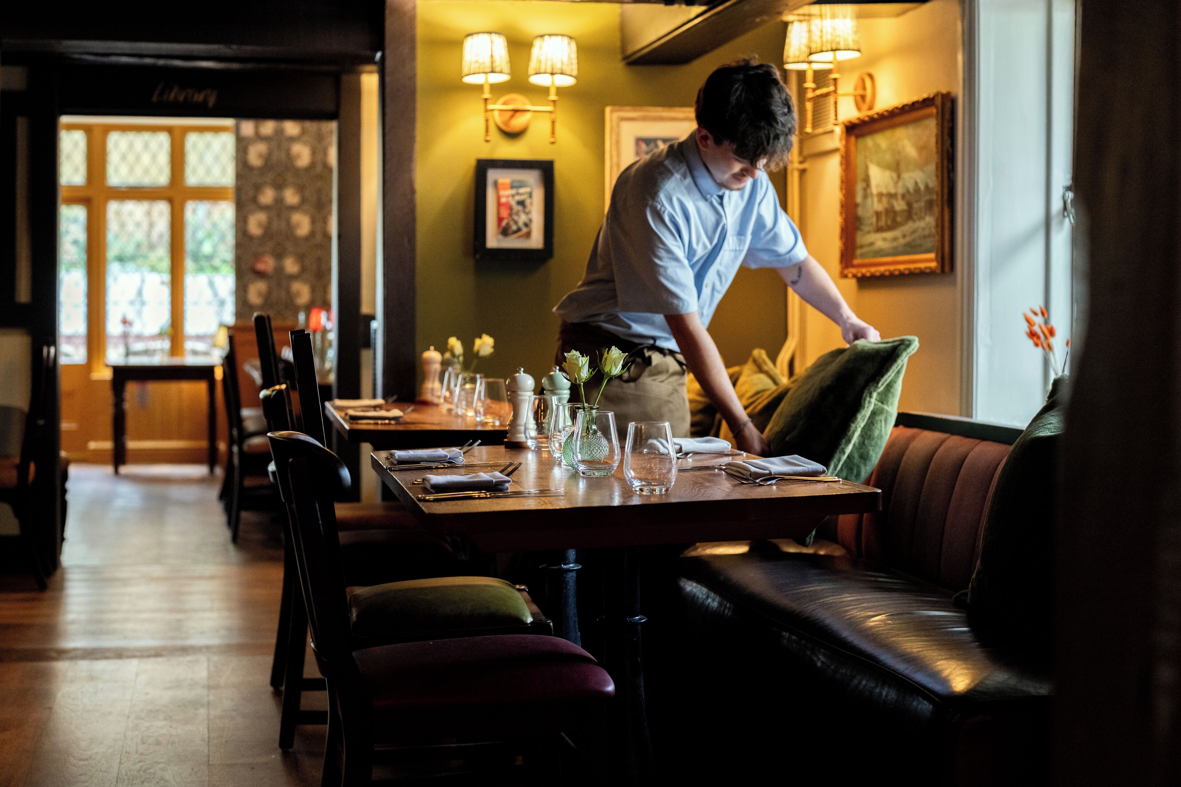 Een restaurantinterieur met houten tafels, comfortabele zitjes en wandlampen.
