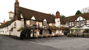 Un pub tradicional con fachada blanca, varias ventanas y un área de estar al aire libre cubierta.