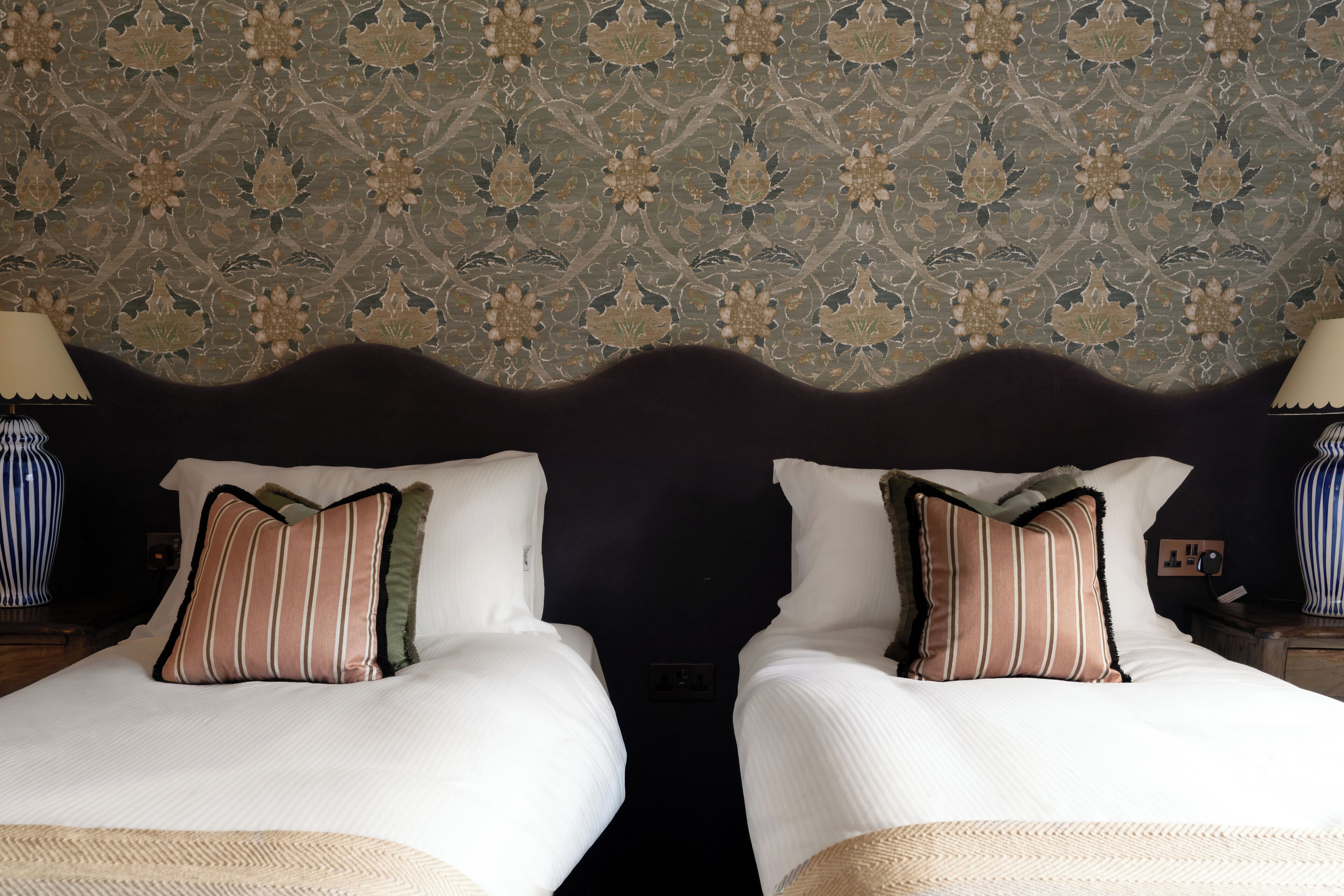 A double bed with striped pillows and a decorative headboard.