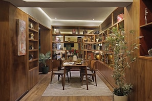 Una habitación con paneles de madera, una mesa de comedor y sillas, rodeada de estanterías con objetos decorativos y libros.