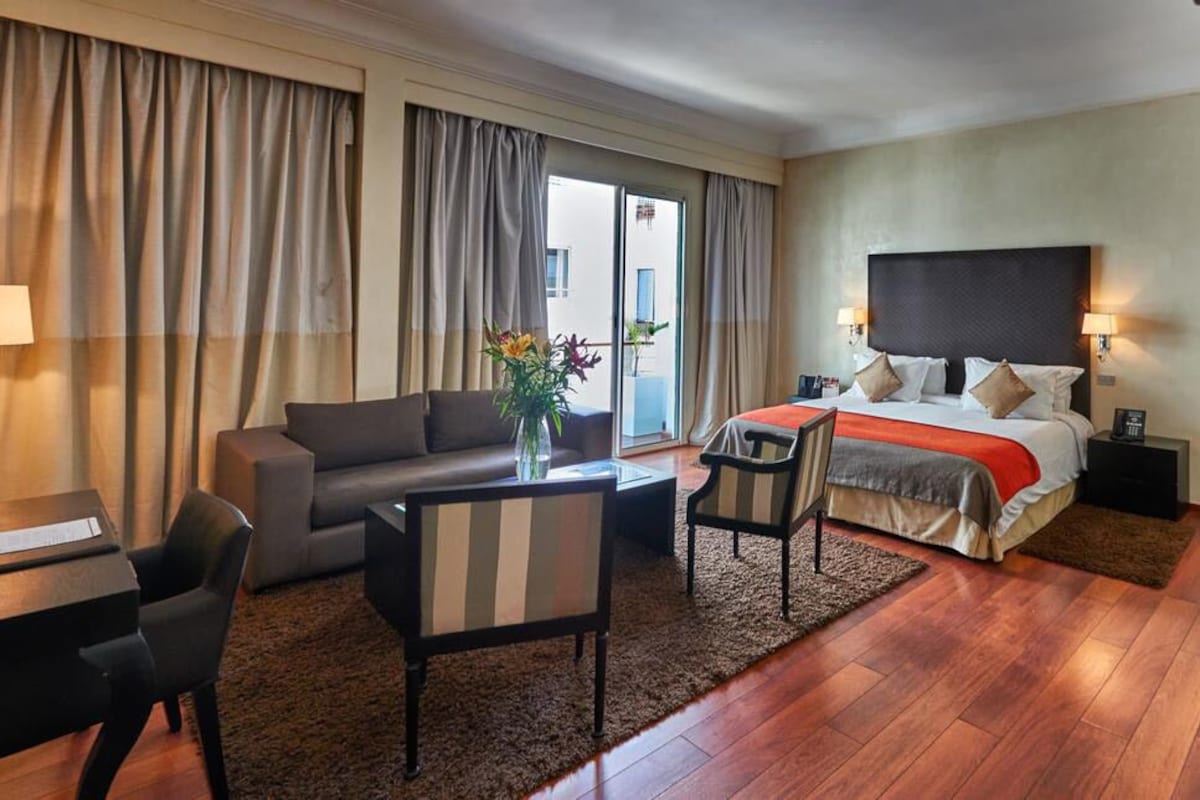 Een hotelkamer met een bed, een bank, een bureau en een stoel.