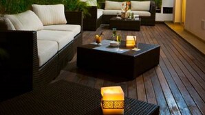 Un espace extérieur aménagé avec des meubles en osier, une table basse en bois et une lanterne.