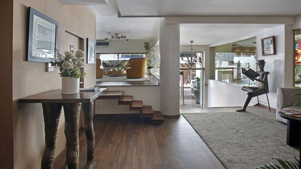 Un intérieur moderne avec un plancher en bois, un escalier et un coin salon comprenant une chaise et une table.
