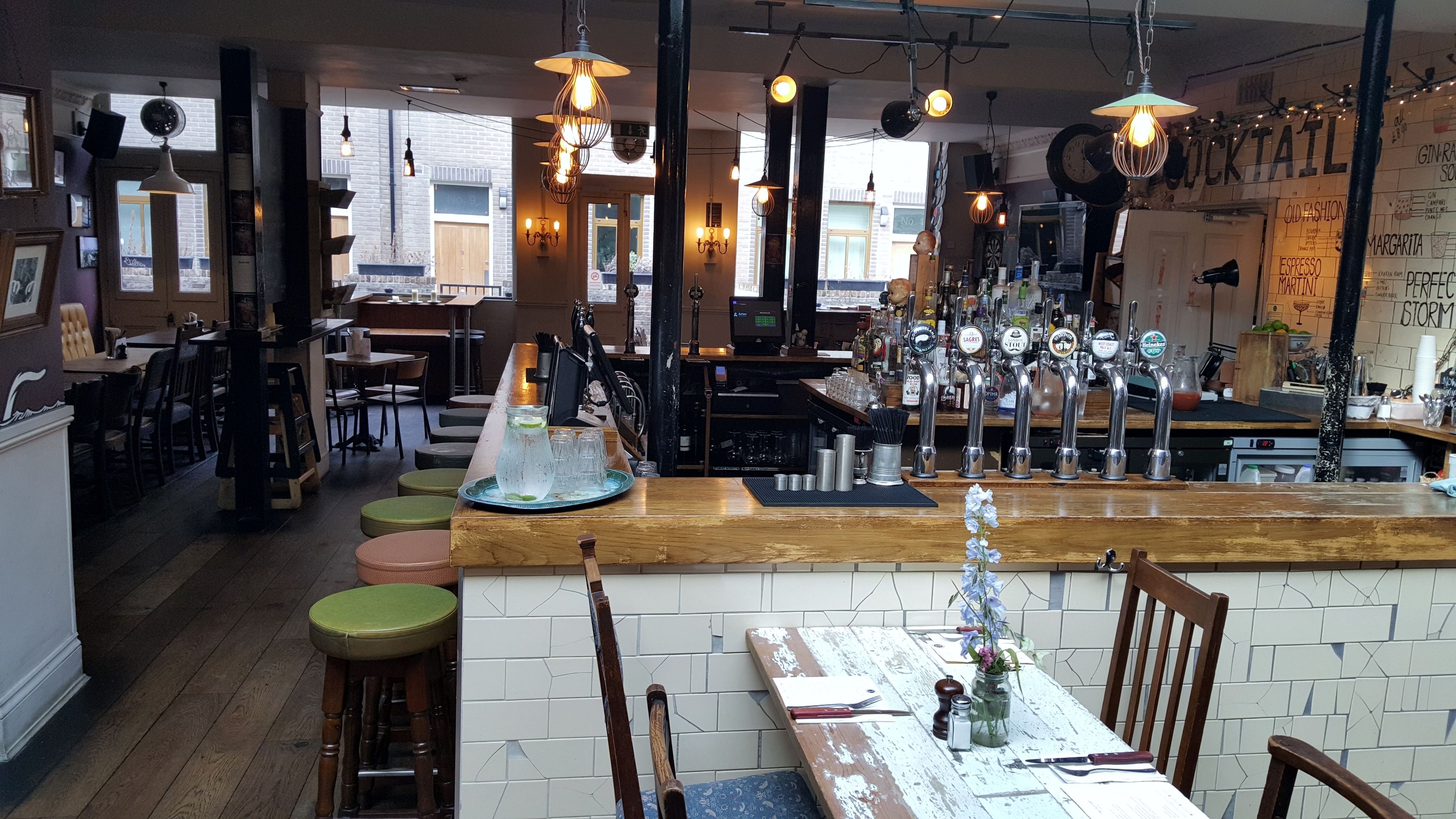 Un espace bar doté d’un comptoir en bois, de plusieurs robinets et de tabourets.