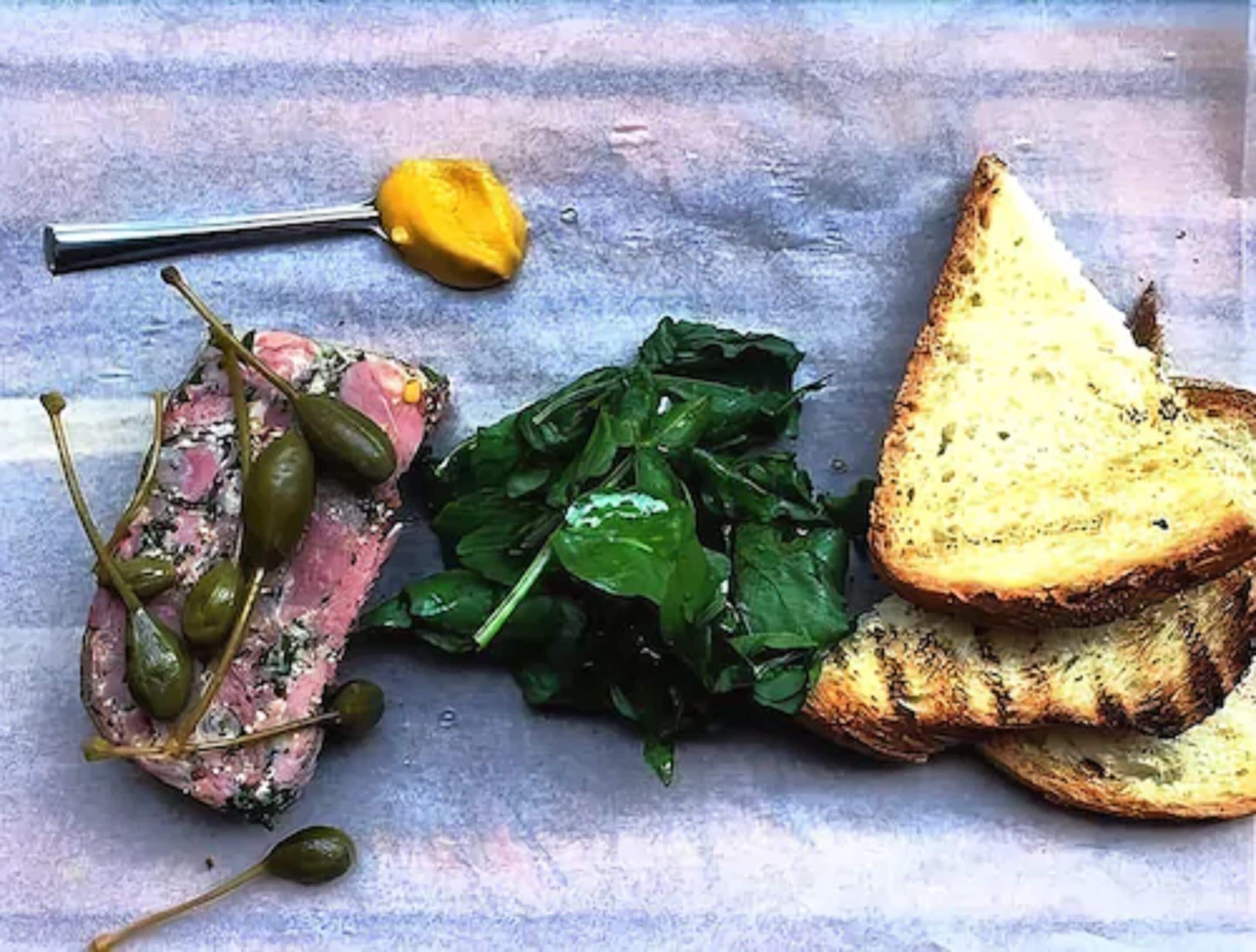 Ein Teller mit Steak, Spinat und gegrilltem Brot.