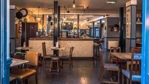 Un restaurant chaleureux avec un coin bar, des meubles en bois et des luminaires suspendus.