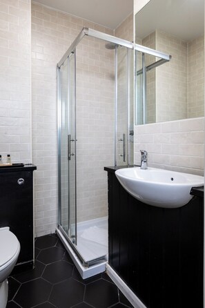 Eenvoudige eenpersoonskamer | Badkamer | Een douche, gratis toiletartikelen, een haardroger, handdoeken