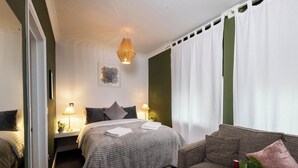 Une chambre d’hôtel comprenant un lit, deux tables de chevet avec des lampes, un canapé, une table en verre avec une bouteille et un verre, et un élément décoratif mural.