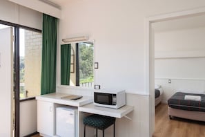 Habitación compacta con kitchenette, una cama y vista a zonas verdes.