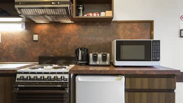 A kitchen with a stove, microwave, toaster, and coffee maker on a wooden countertop.