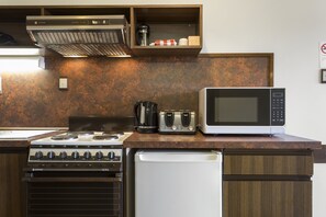 Una cocina con estufa, microondas, tostadora y cafetera sobre una encimera de madera.