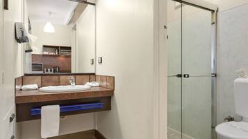 A modern bathroom with a glass shower enclosure, a sink with a mirror, and a towel rack.