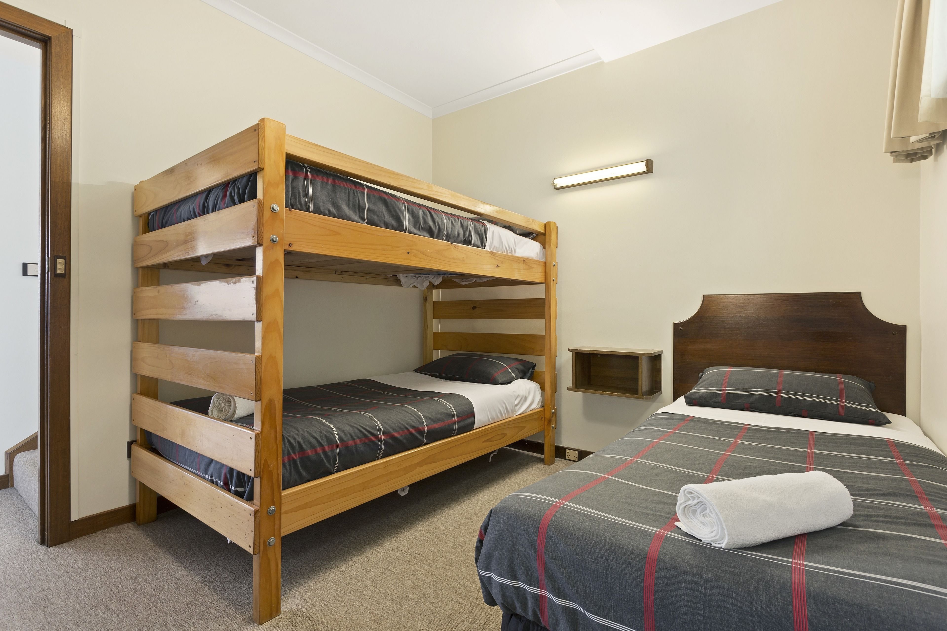 A bunk bed room with a single bed and a wooden headboard.