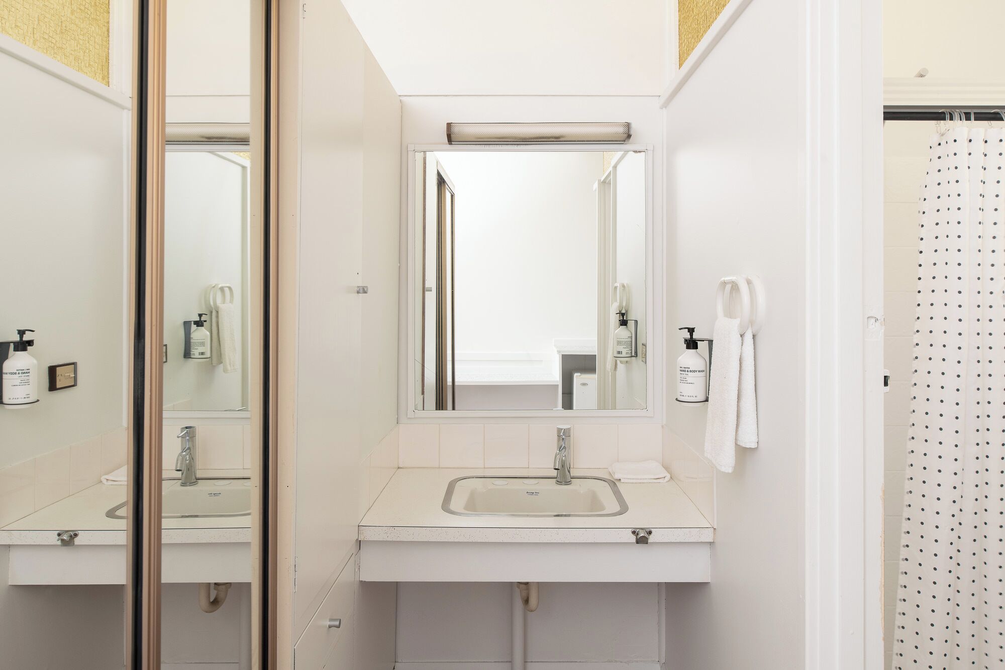 A modern bathroom with a large mirror, a sink, and a shower area.