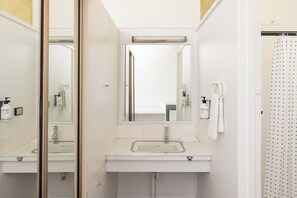 Une salle de bain moderne avec un grand miroir, un lavabo et un espace douche.