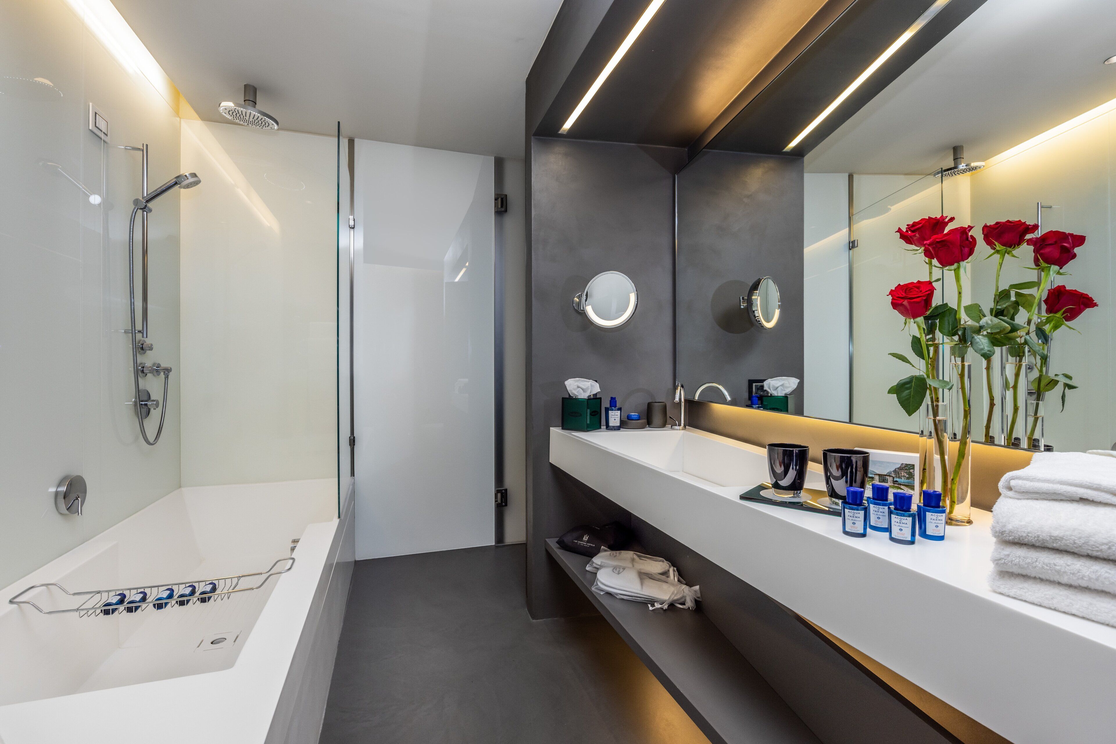 Ein modernes Badezimmer mit einer Badewanne, einer Dusche und einem Waschtisch mit Spiegel und Rosenblumen.