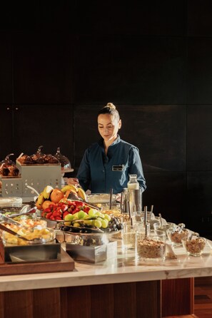 A buffet setup with various food items and a server. - Lido Palace - The Leading Hotels of the World (Riva del Garda)