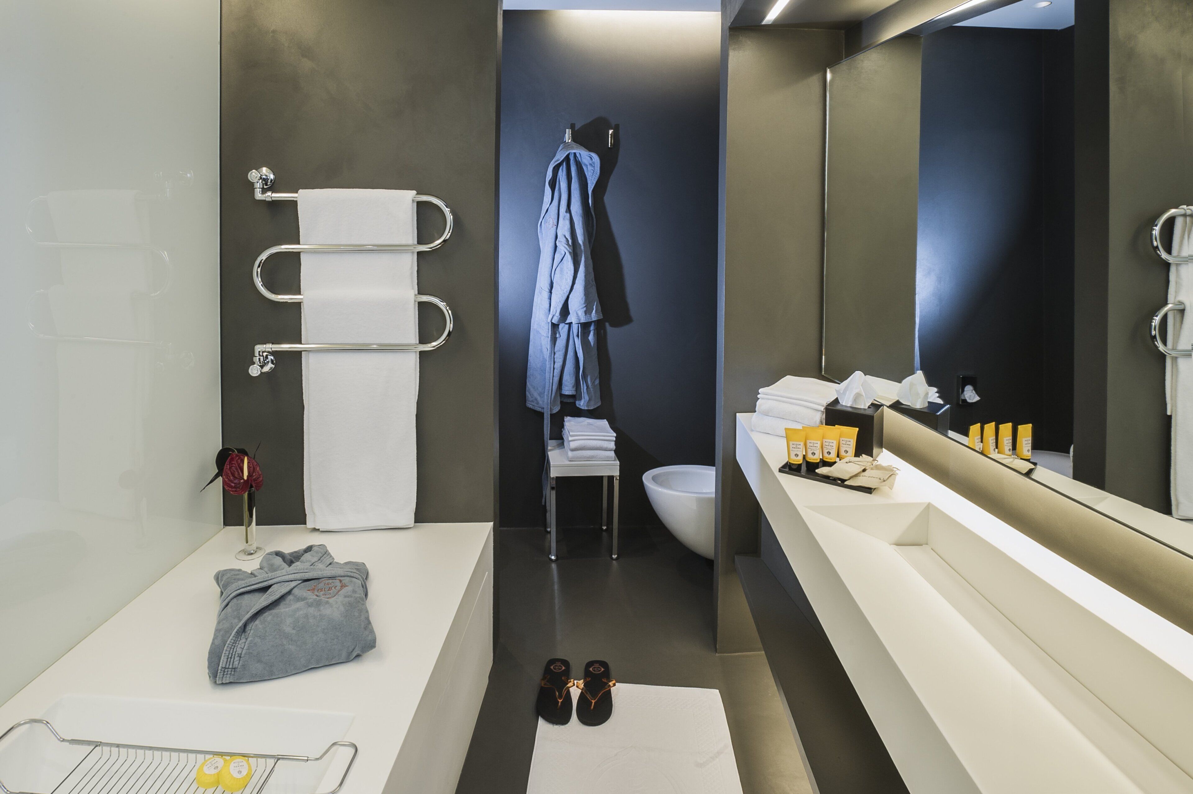 A modern bathroom with a white sink, a large mirror, and a towel rack.