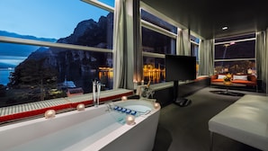A modern bathroom with a bathtub, large windows, and a view of a mountainous landscape. - Lido Palace - The Leading Hotels of the World (Riva del Garda)
