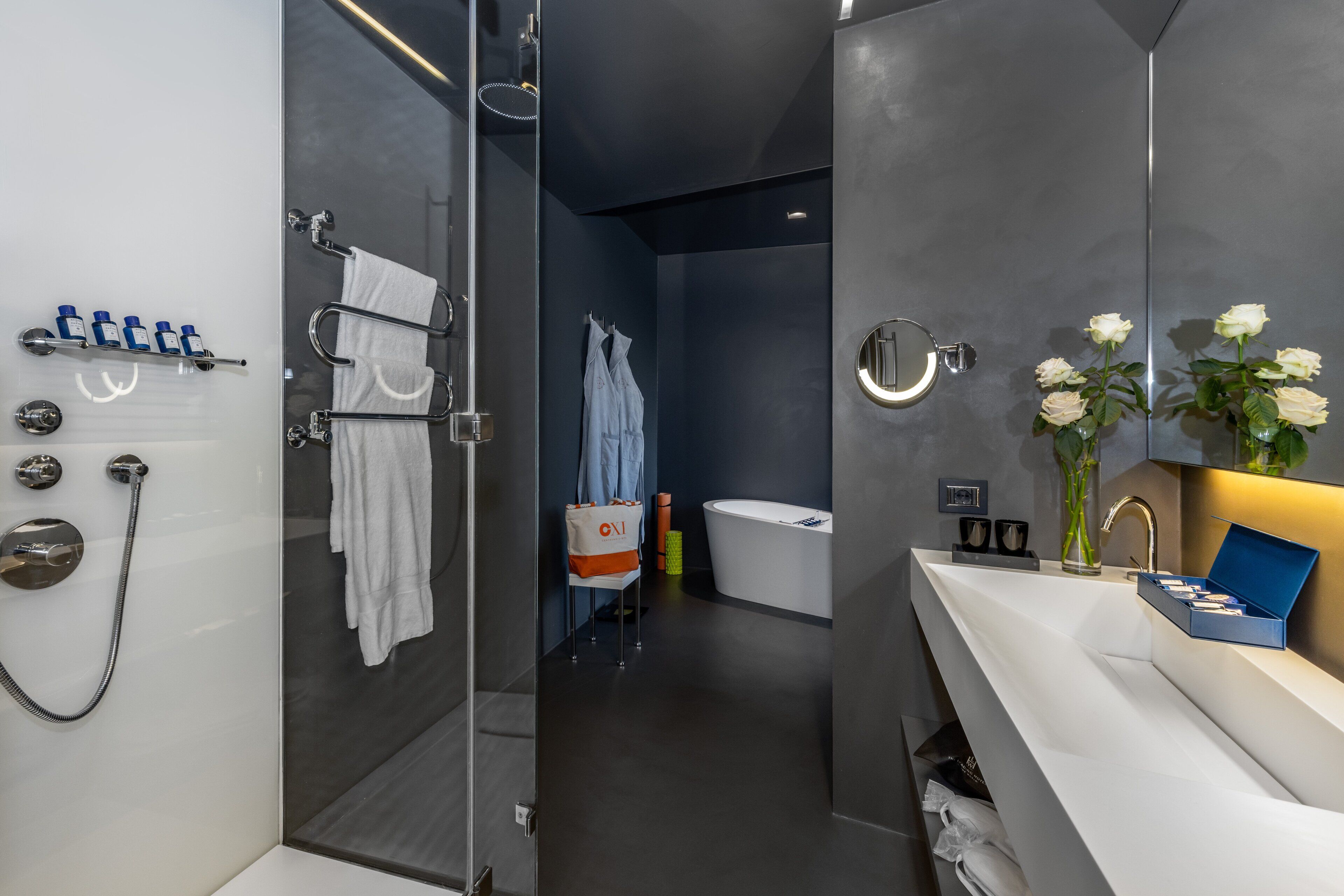 A modern bathroom with a glass-enclosed shower, a white bathtub, and a vanity with a mirror.