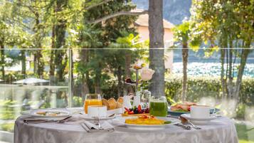Una mesa dispuesta para el desayuno, con tostadas, fruta y una taza, con vistas a un área exterior pintoresca.