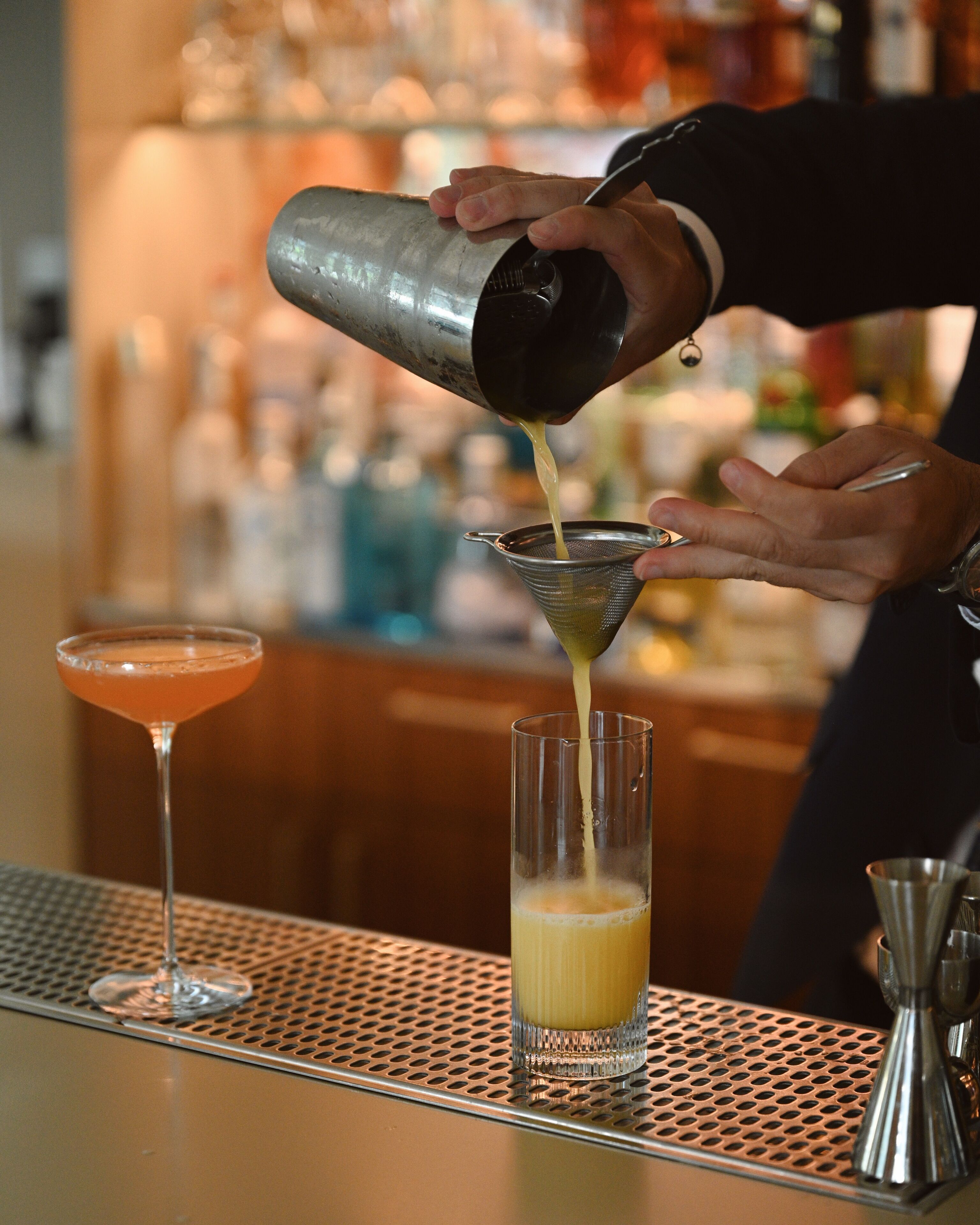 Un barman verse une boisson dans un grand verre.