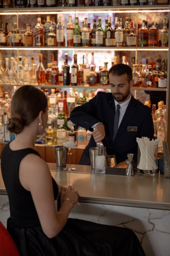 A bar with a bartender preparing a drink behind the counter.