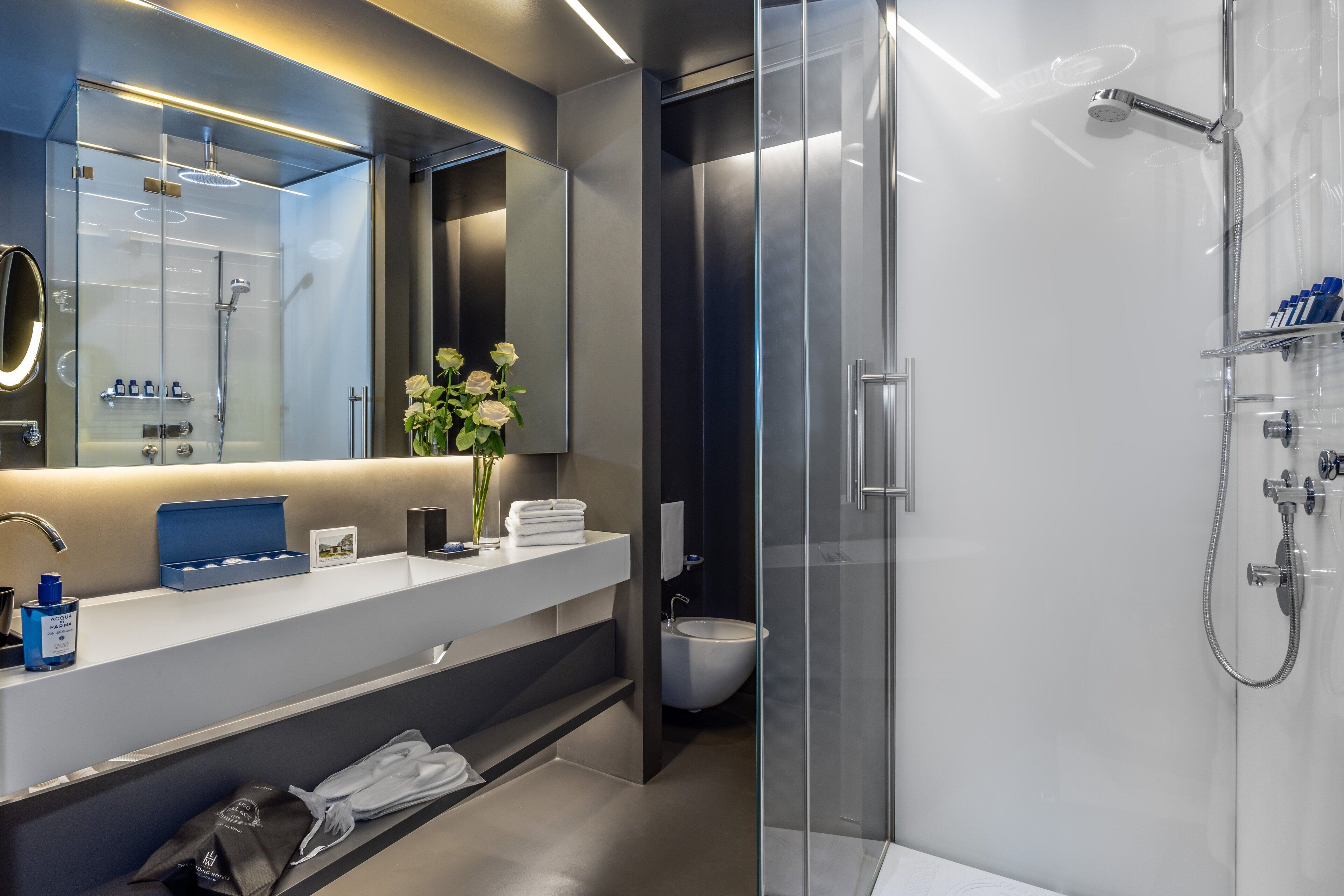 Un baño moderno con ducha de vidrio, tocador con espejo y retrete.
