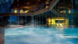 A modern building with a glass facade, a heated pool, and outdoor seating areas. - Lido Palace - The Leading Hotels of the World (Riva del Garda)