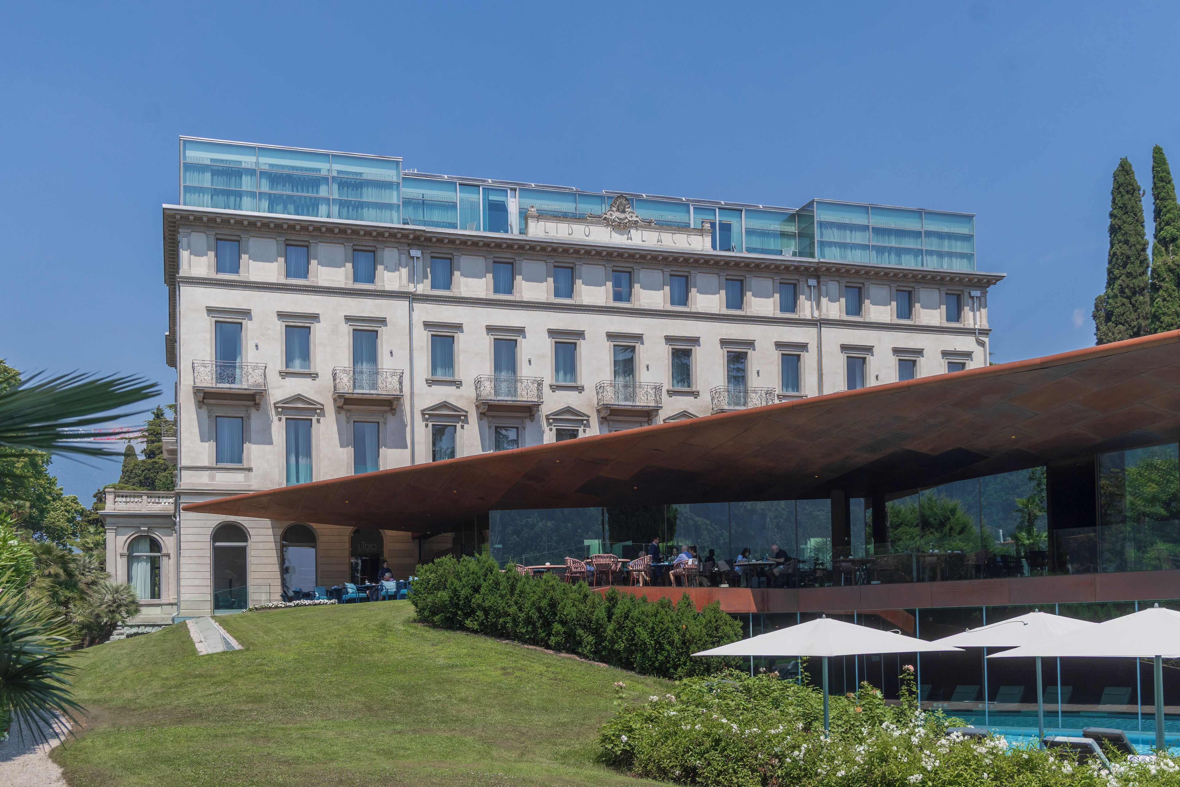 Un hotel con un edificio grande, zona de estar al aire libre y piscina.