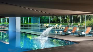 Una piscina techada, una piscina al aire libre, sombrillas