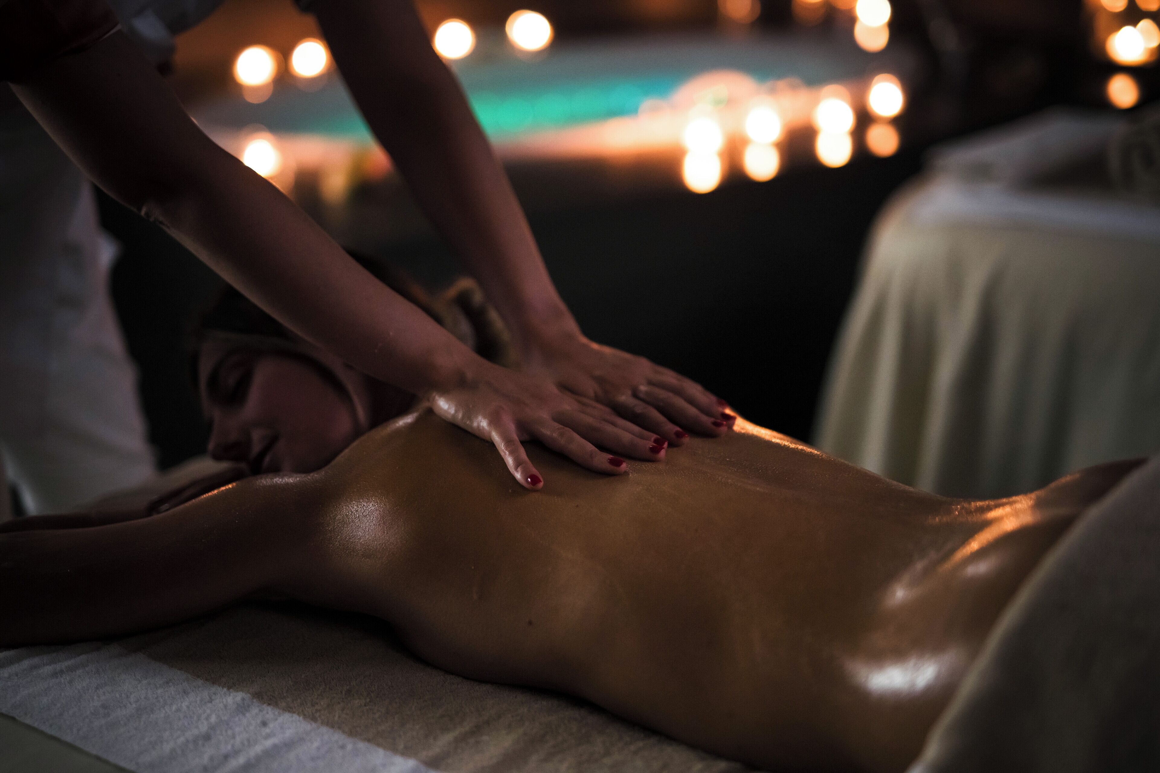 Eine Massageanwendung, wobei eine Person bäuchlings auf einer Massageliege liegt.