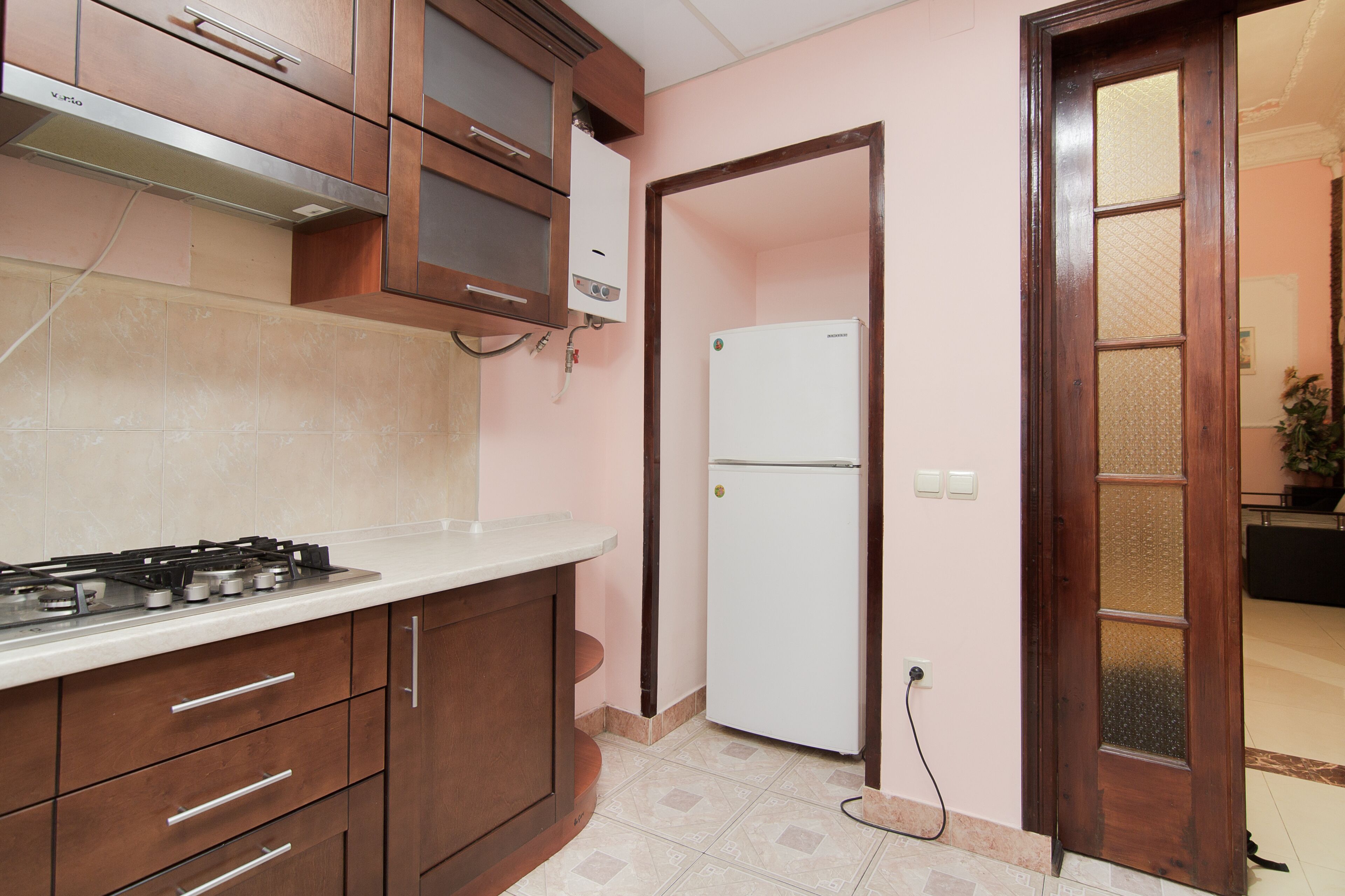 Eine Küche mit Holzschränken, einer weißen Arbeitsplatte, einem Gasherd und einem weißen Kühlschrank.