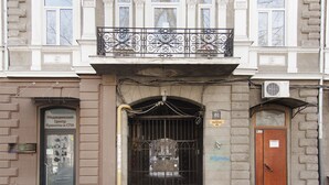 A building with a gated entrance, a balcony with ornate metal railings, and a sign indicating a medical center.