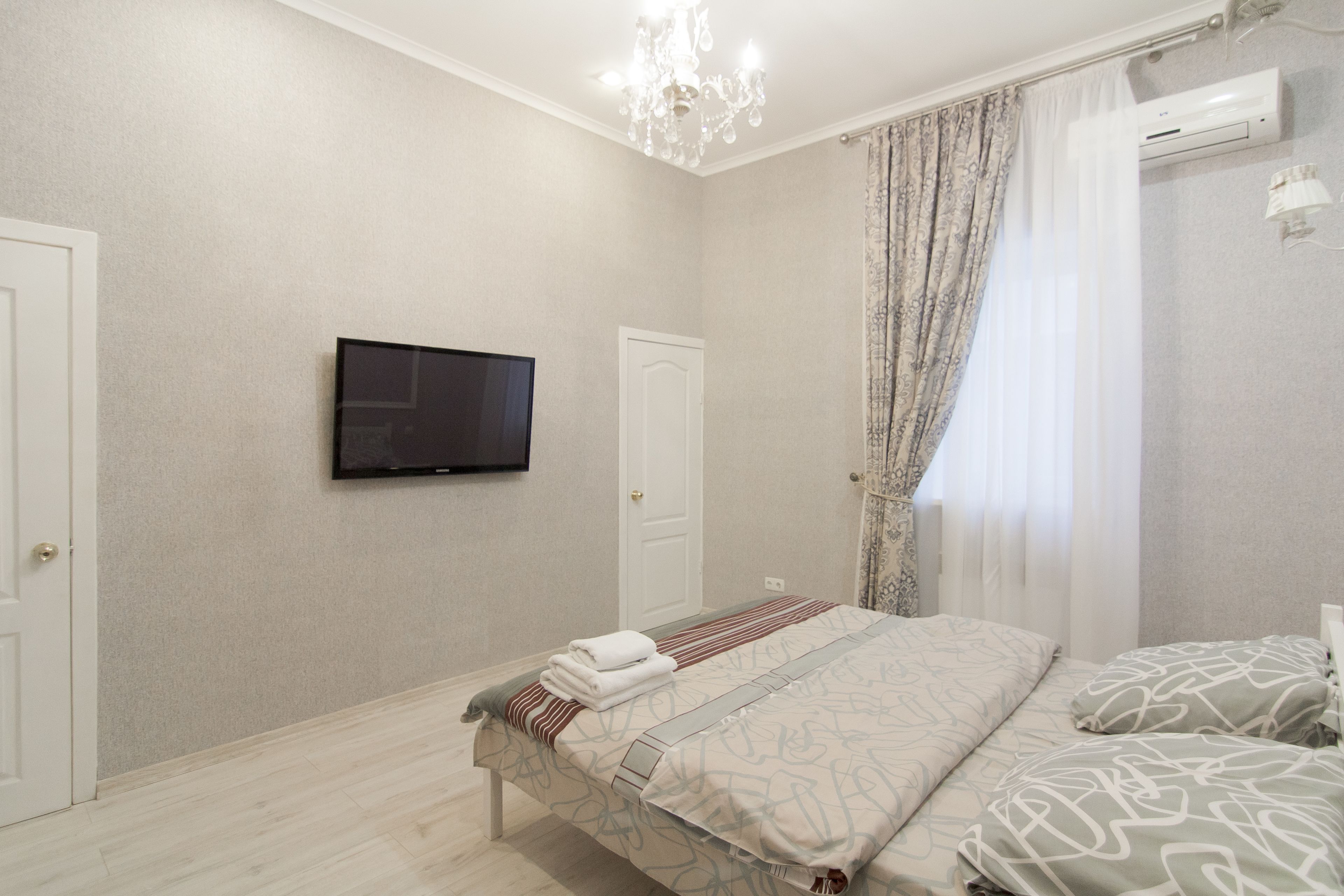 A bedroom with a bed, a television, and a window with curtains.