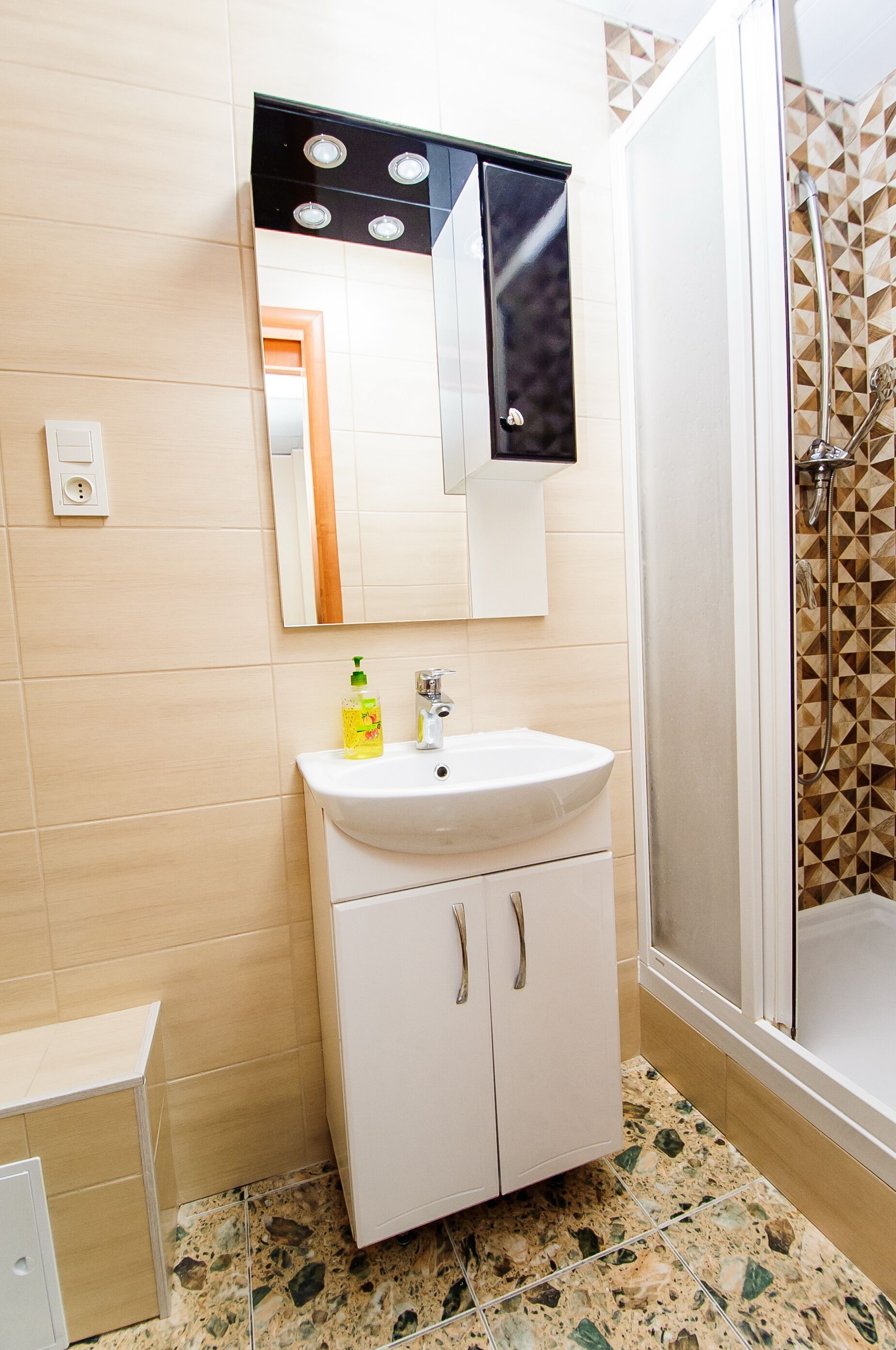 Un baño con lavamanos, espejo y ducha.