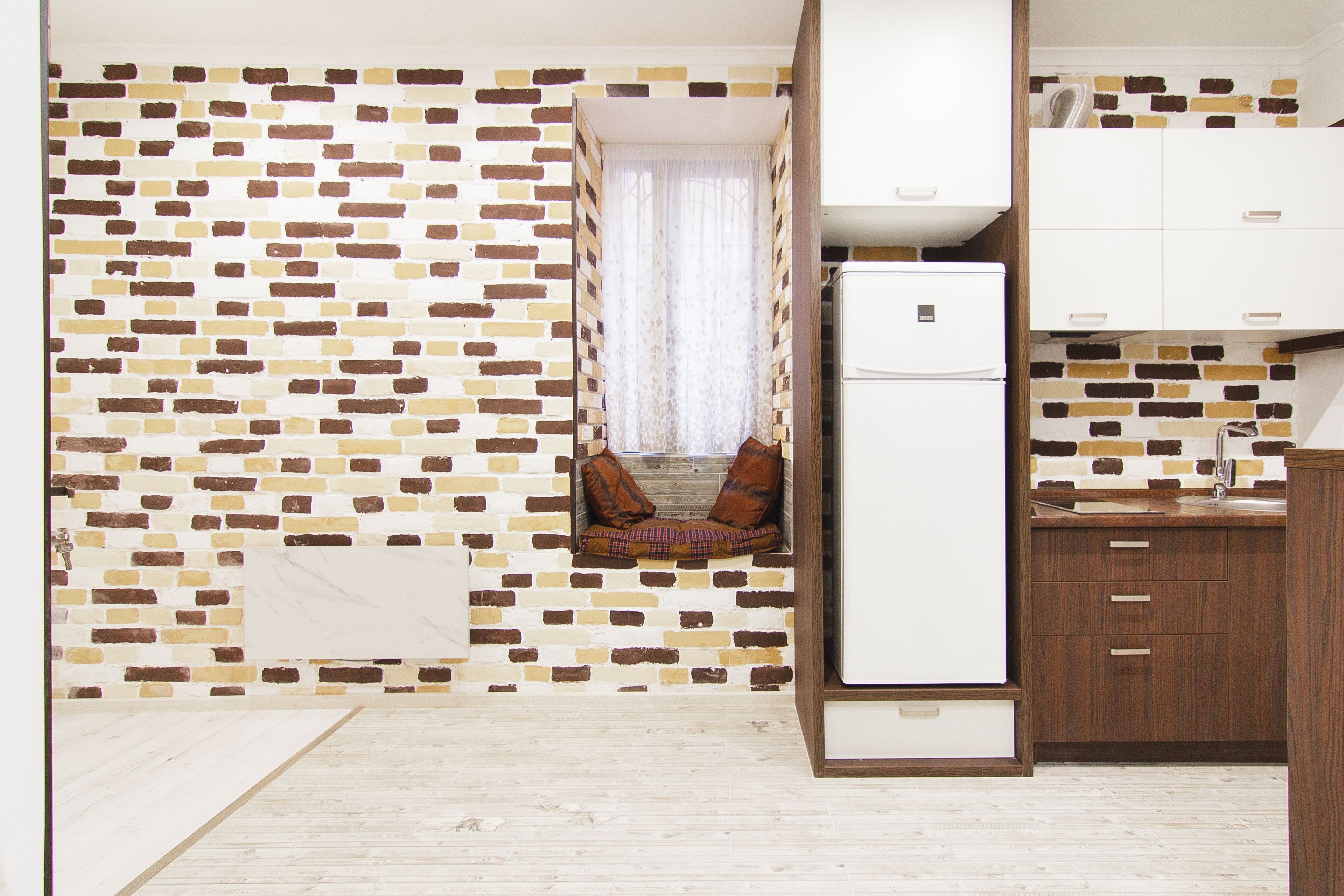 Una cocina compacta con refrigerador, gabinetes de madera y un salpicadero de ladrillo.