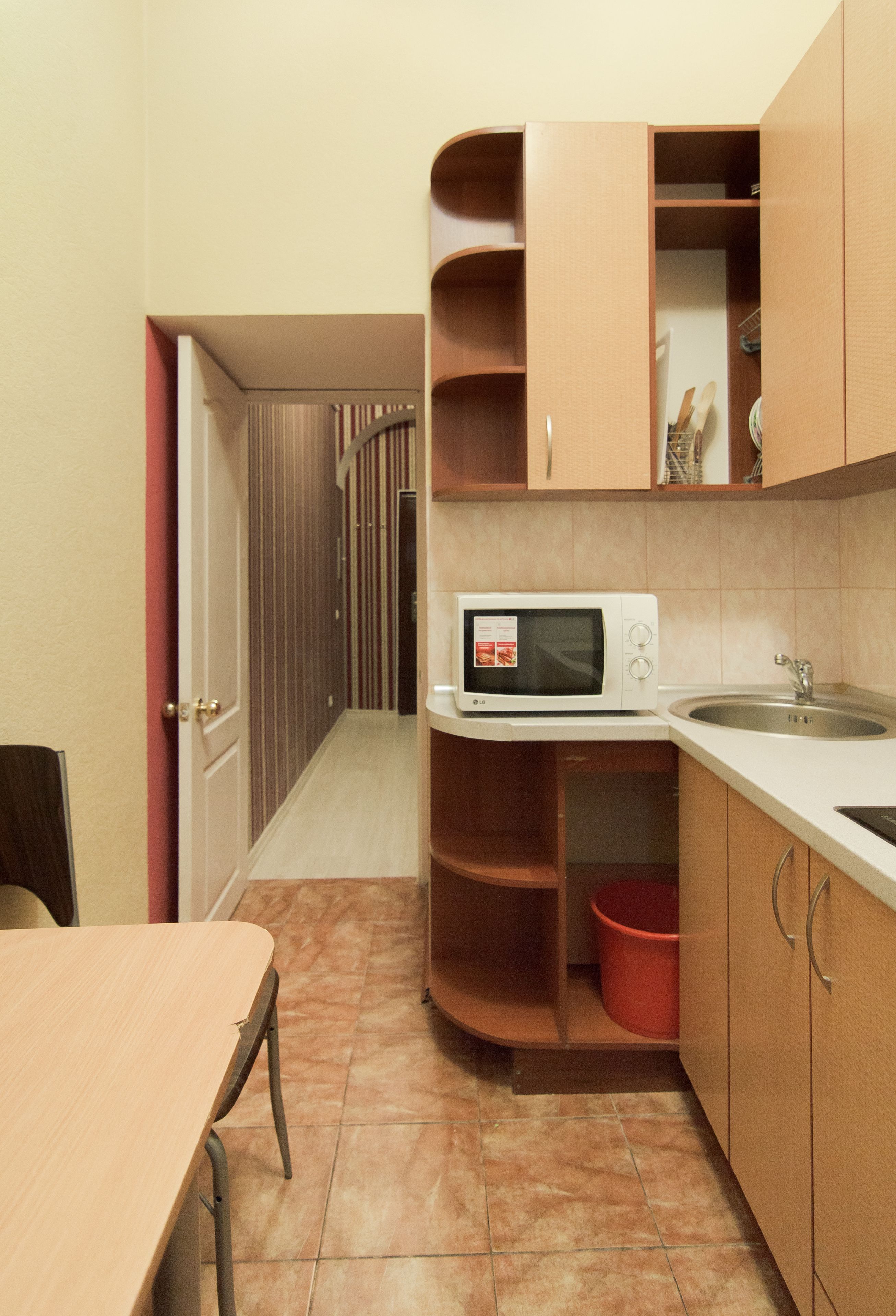 A compact kitchen with a microwave, sink, and wooden cabinets.