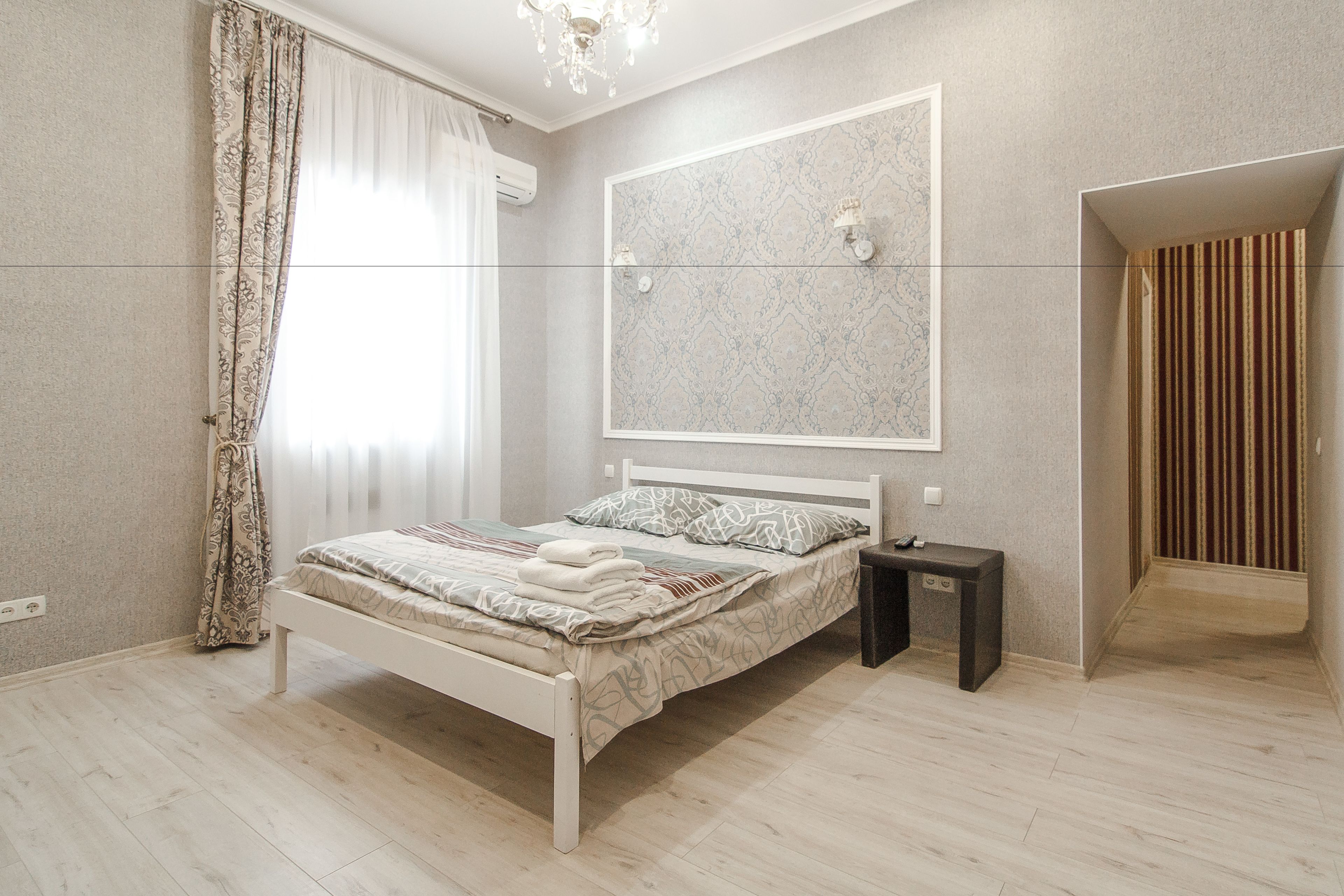 Quarto com cama, mesa de cabeceira e um espelho grande na parede.