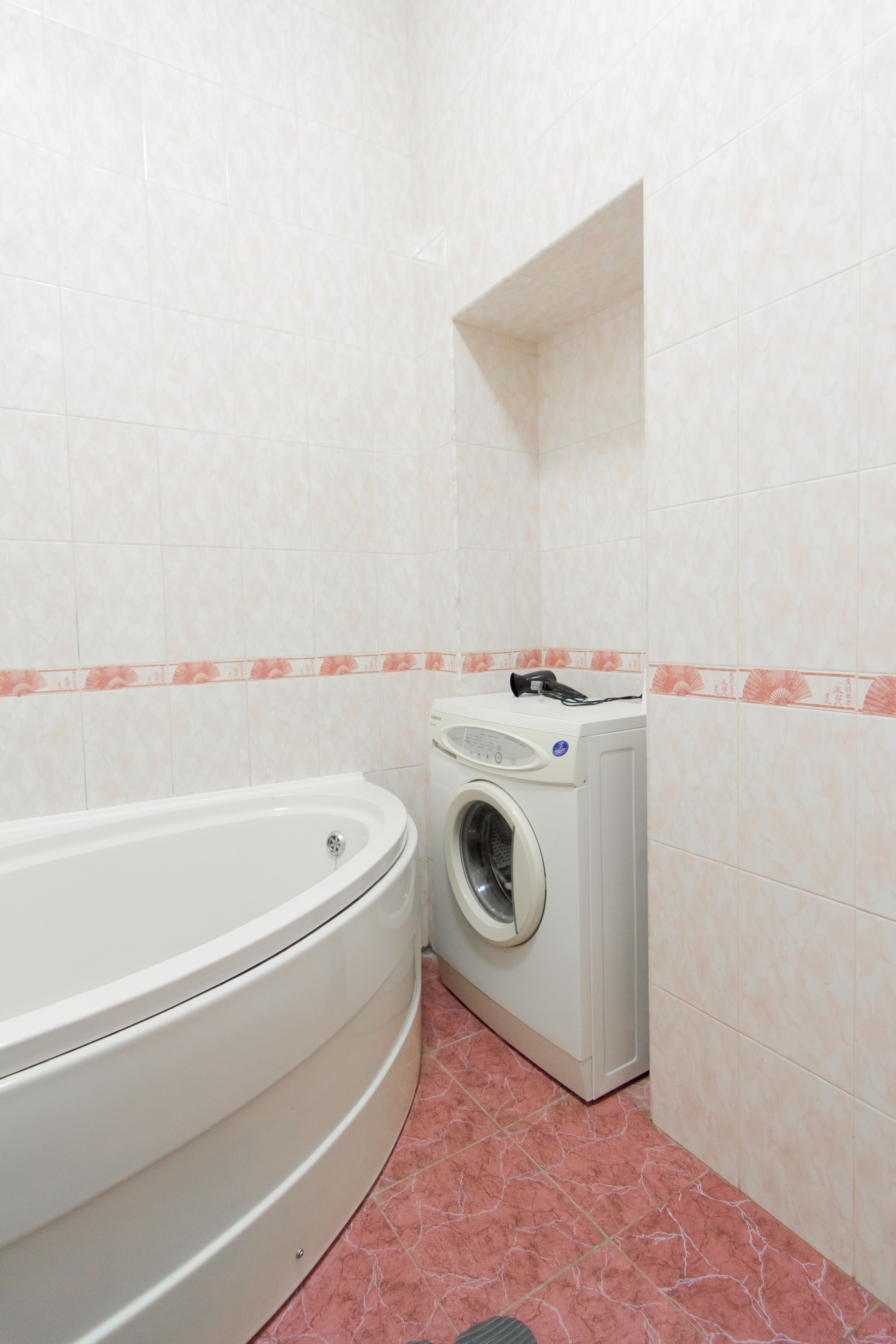 Un baño con bañera y lavadora de carga frontal.
