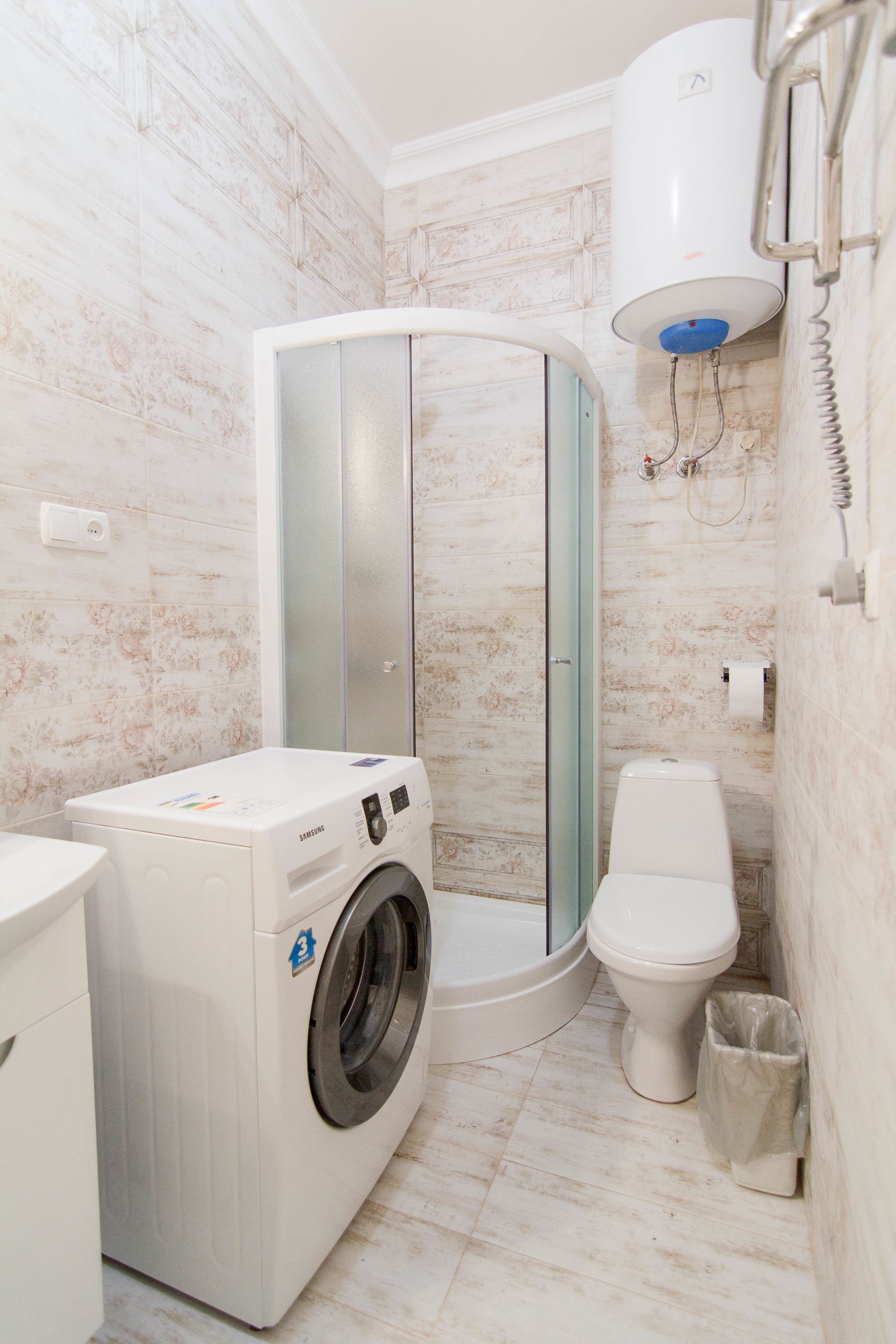 Ein kleines Badezimmer mit Waschmaschine, Toilette und einer Duschkabine.